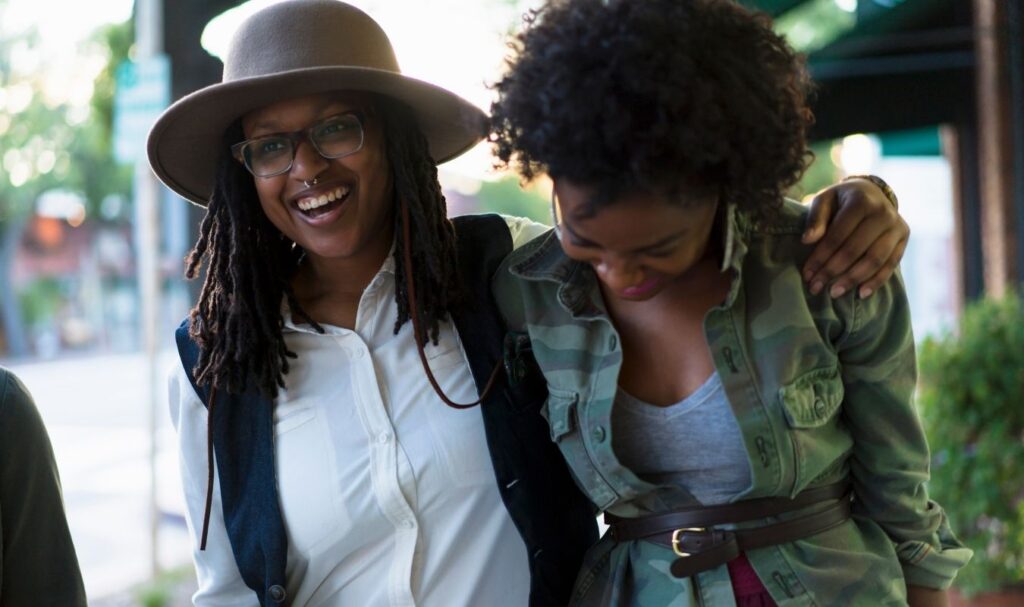 two friends walking down the street together smiling