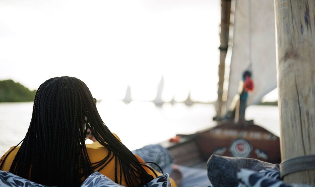 woman sitting on dhow boat looking at the sunset