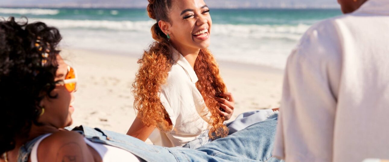 group of women sitting together on beach laughing