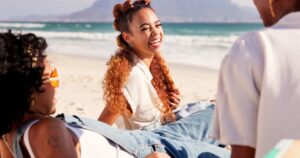 group of women sitting together on beach laughing