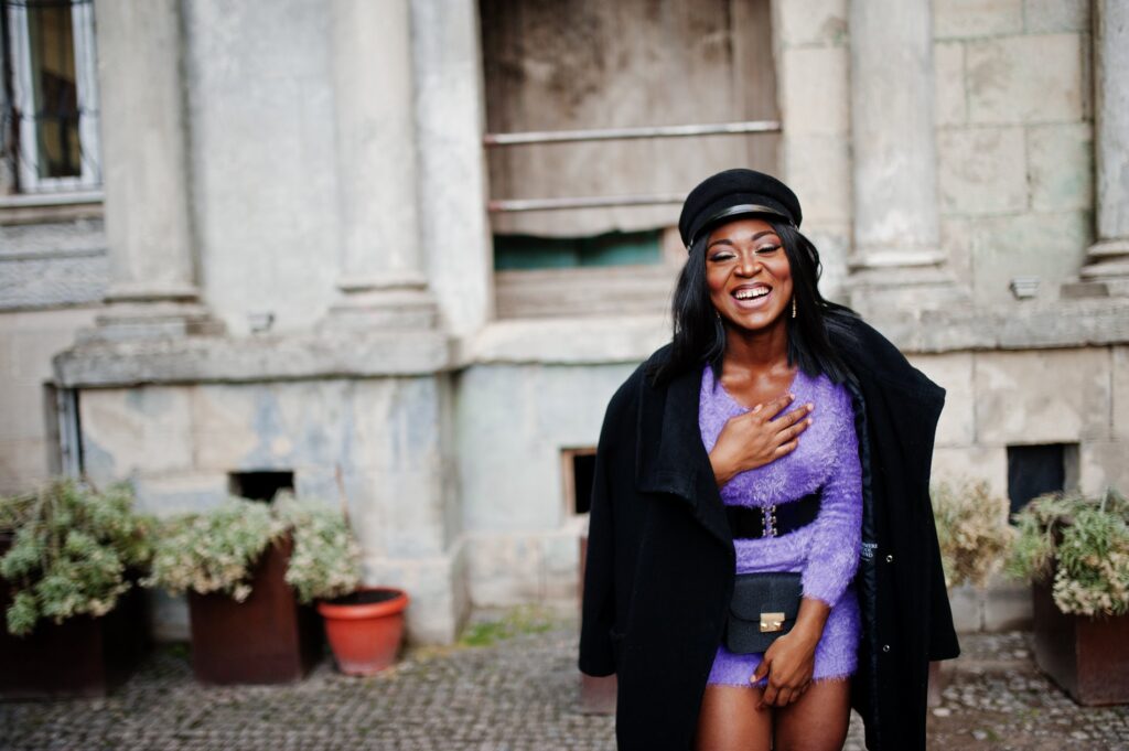 Smiling Black woman in purple dress and black coat