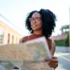 woman staring off into the distance as she holds a city map in the street