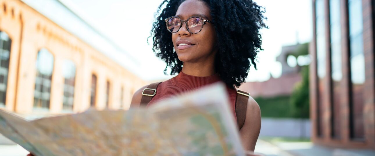 woman staring off into the distance as she holds a city map in the street
