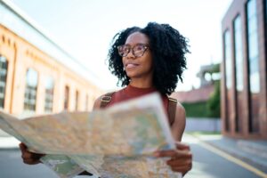 woman staring off into the distance as she holds a city map in the street