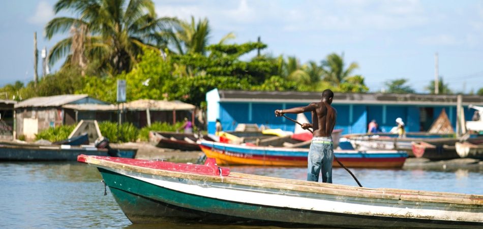 wooden boats in water in Jamaica with man rowing in foreground